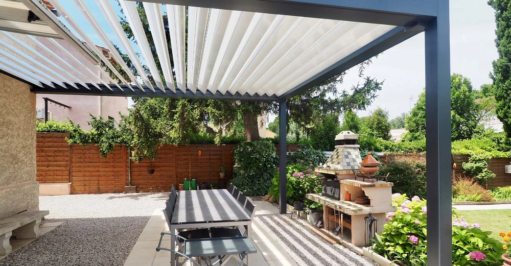 Pergola bioclimatique à lames orientables en aluminium anthracite, installée sur terrasse pavée