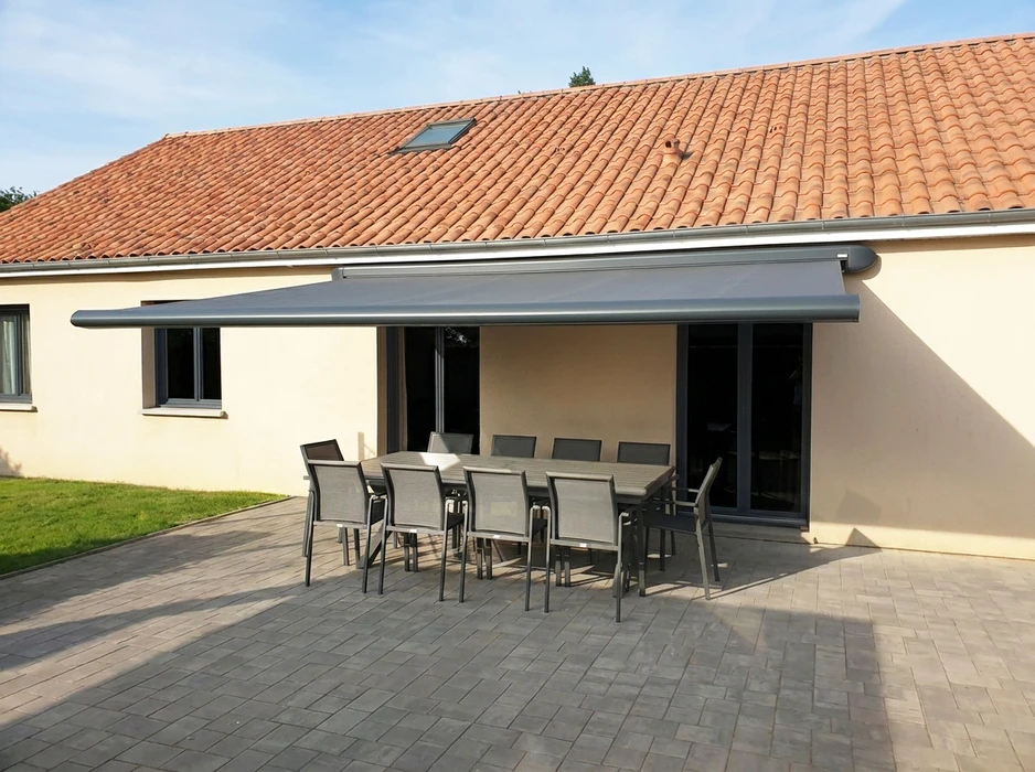 Store banne rétractable à cassette grise anthracite, fixée en façade d'une maison provençale