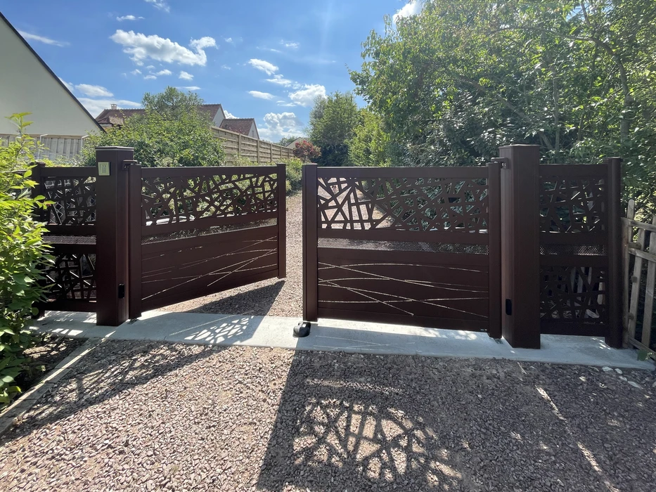 Portail extérieur en aluminium marron avec design décoratif géométrique, installé sur dalle béton dans jardin résidentiel