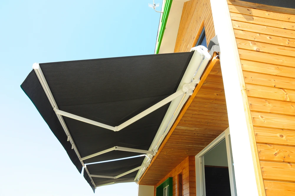 Balcon aménagé avec table et chaises pliantes en bois teck, coussins blancs