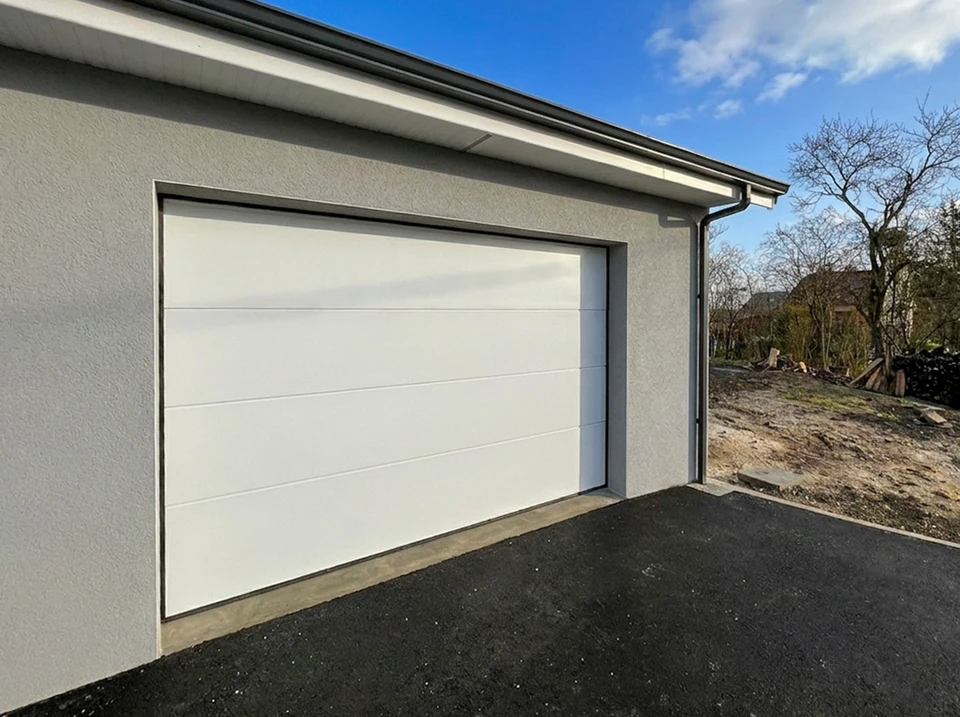 Extérieur résidentiel moderne avec porte de garage sectionnelle anthracite à panneaux horizontaux intégrée dans façade bicolore gris foncé et blanc